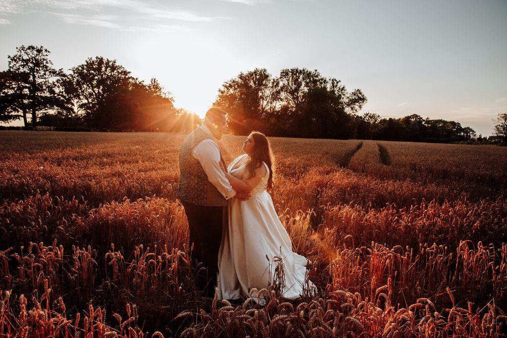 bride and groom in wheat field at sunset