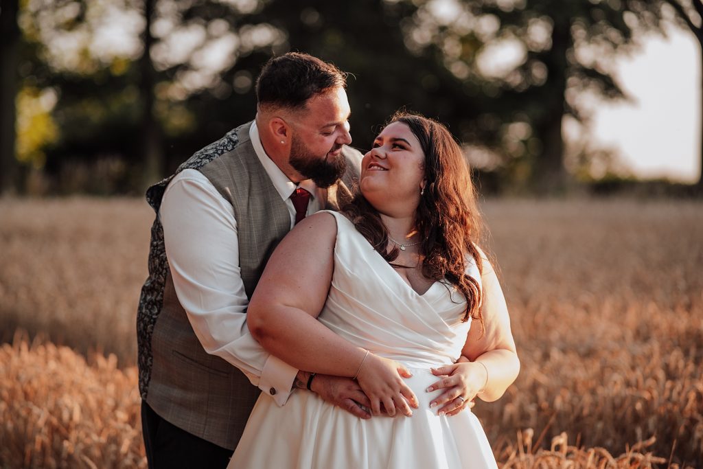 bride and groom in wheat field at sunset