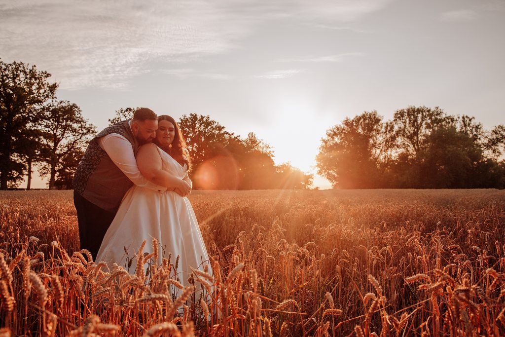 bride and groom in wheat field at sunset