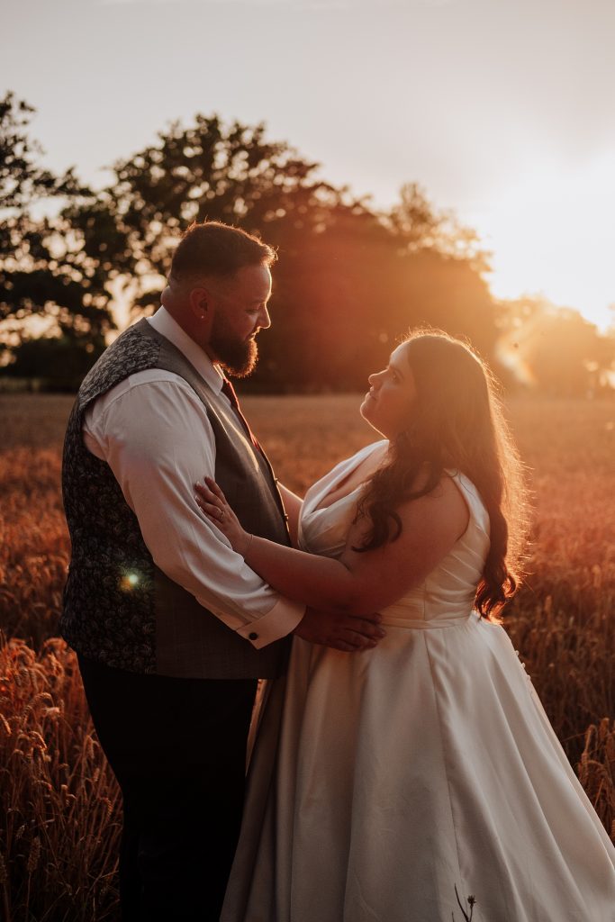 bride and groom in wheat field at sunset