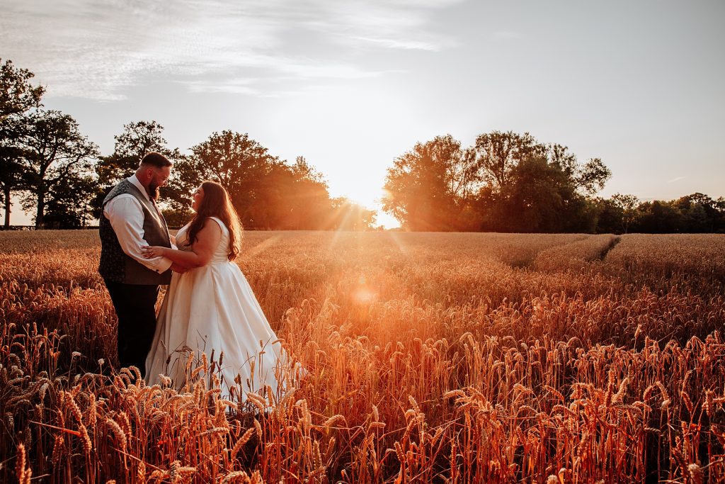 bride and groom in wheat field at sunset