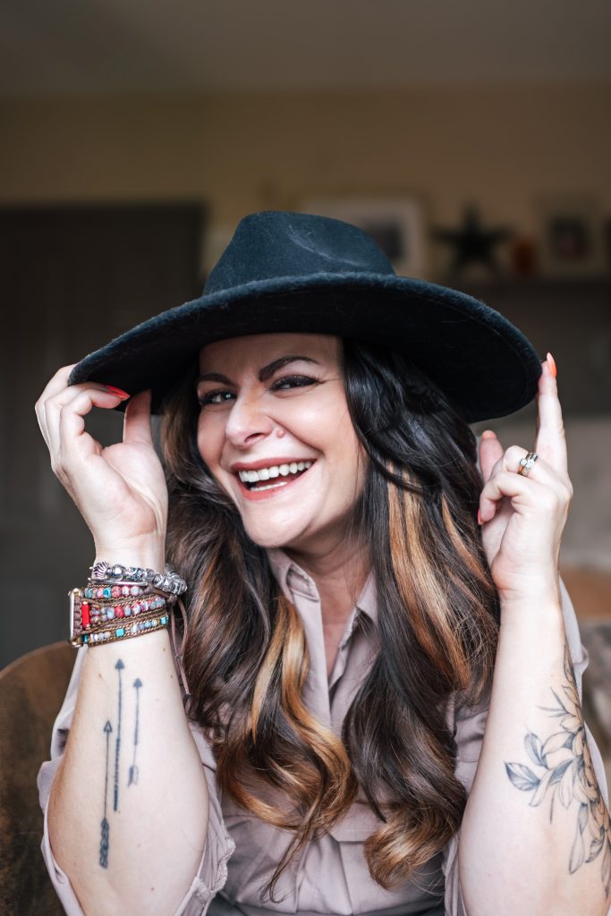 woman with long dark hair looks into camera from under a black hat