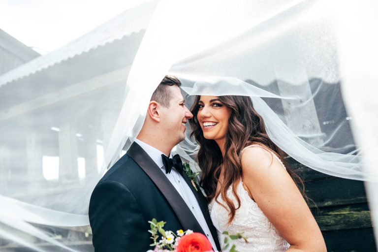 Bride and groom under billowing veil at The Barns at Lodge Farm