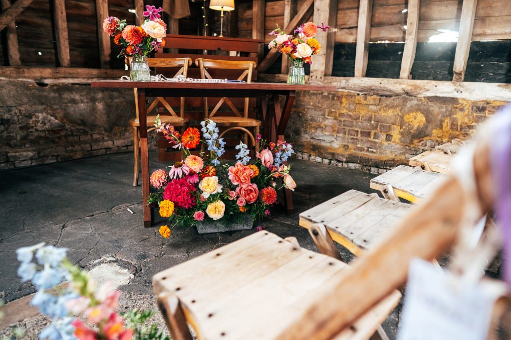 view of table in ceremony barn adorned with pink and orange blooms
