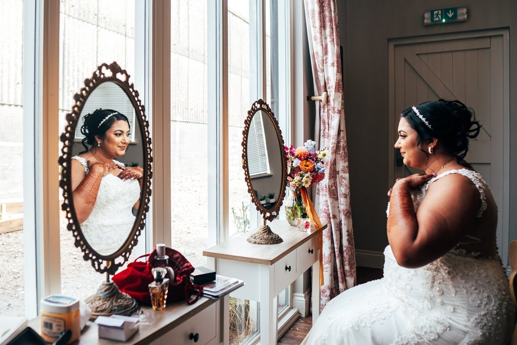bride and her reflection in mirror as she adjusts her necklace