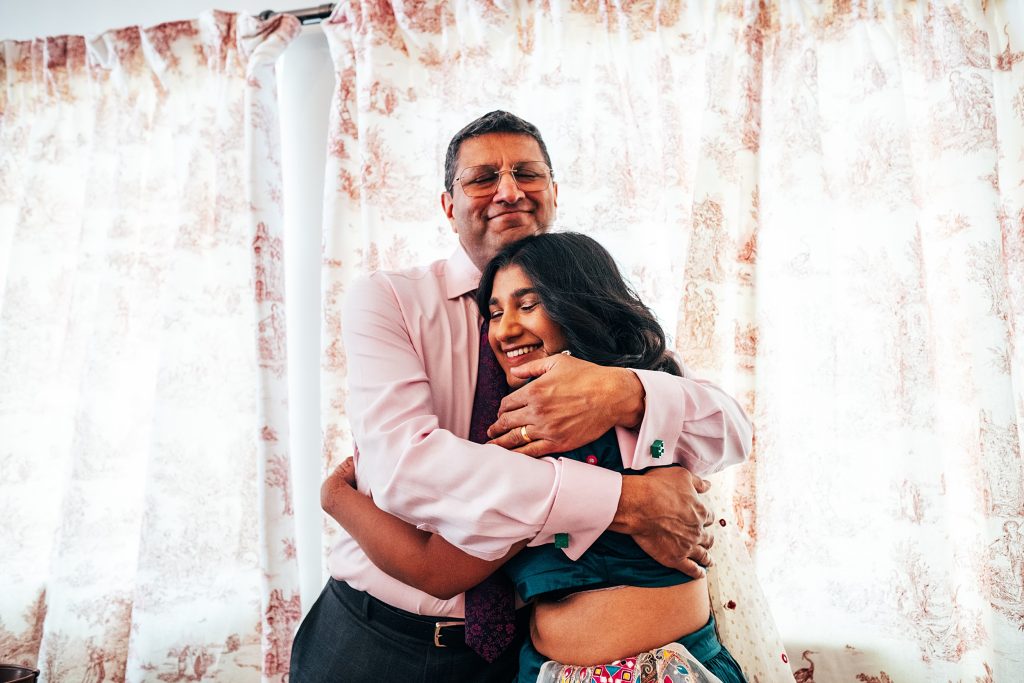 Brides dad hugs his younger daughter