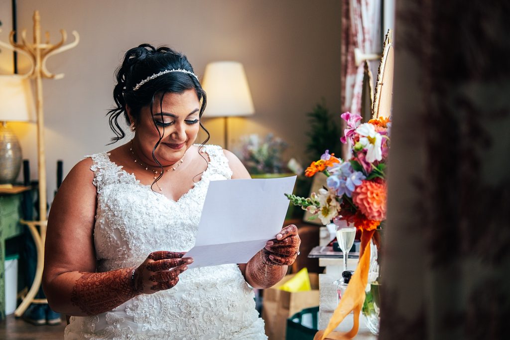 bride sits in prep room and reads a letter from her groom before ceremony