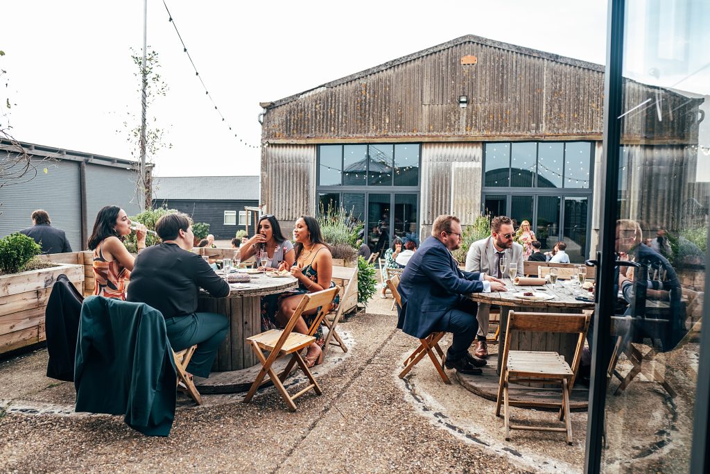 wedding guests sit at tables outside and enjoy afternoon tea