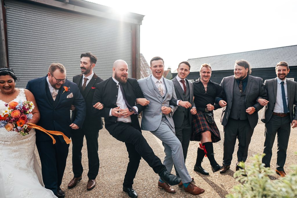 bride groom and guests dance in courtyard on farm