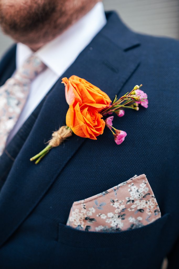close up of grooms orange button hole