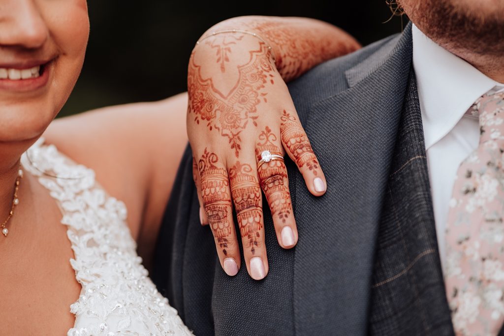 close up of brides wedding ring on her hand decorated with henna