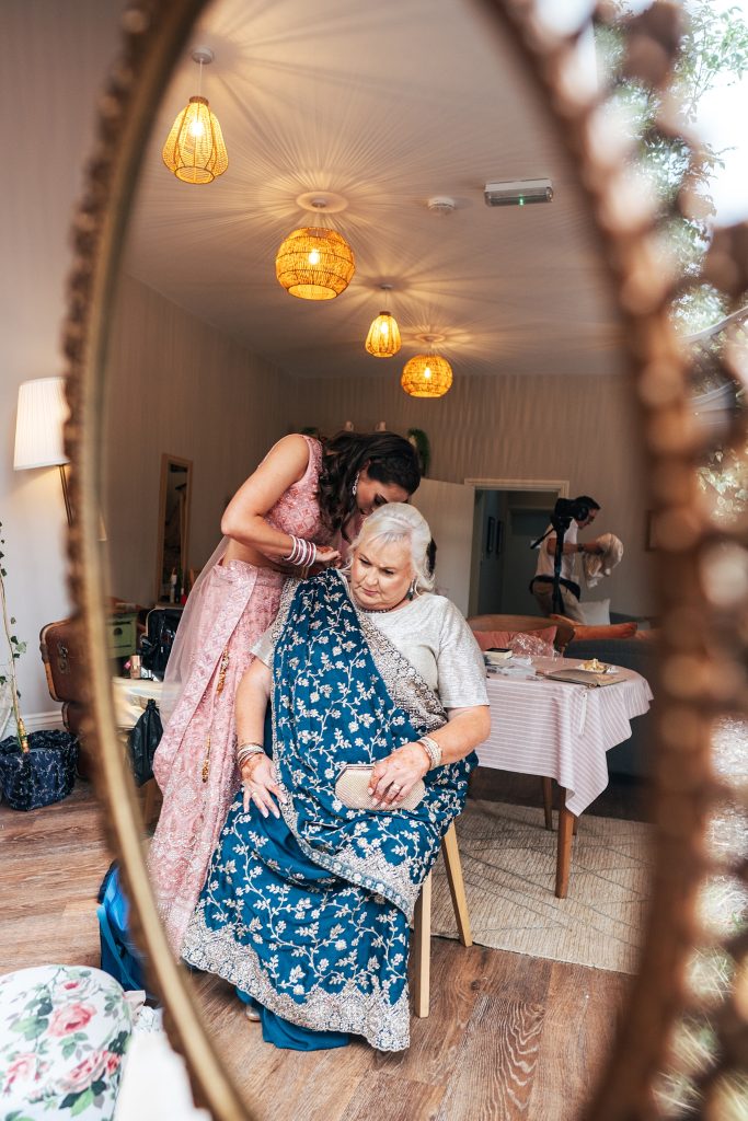 grooms sister helps mum put on traditional sari