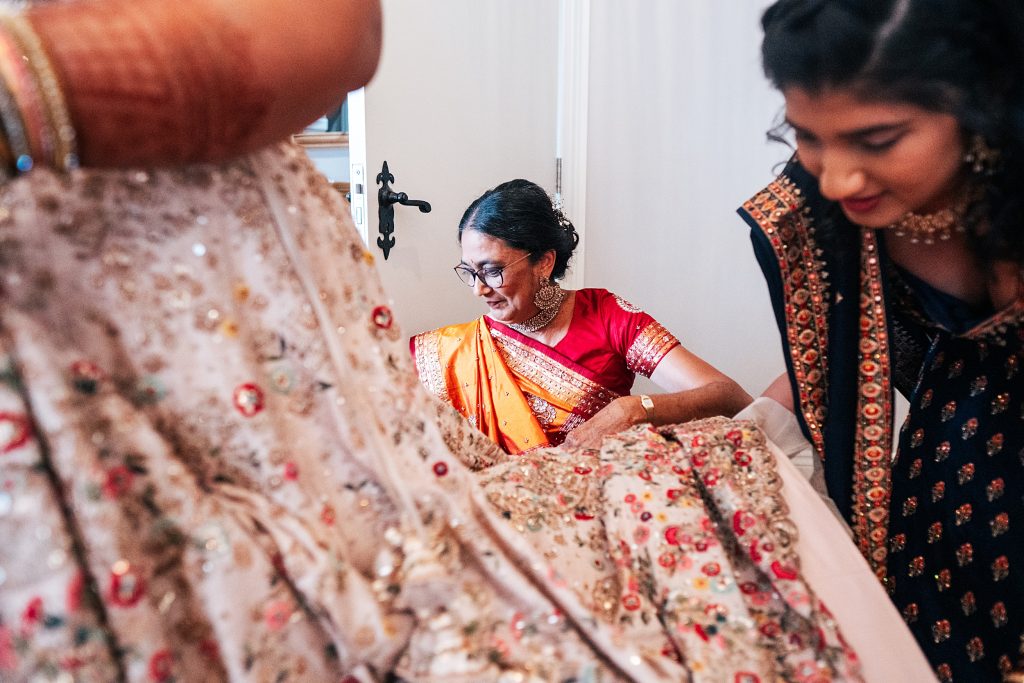 brides mum and sister help with her Lehenga