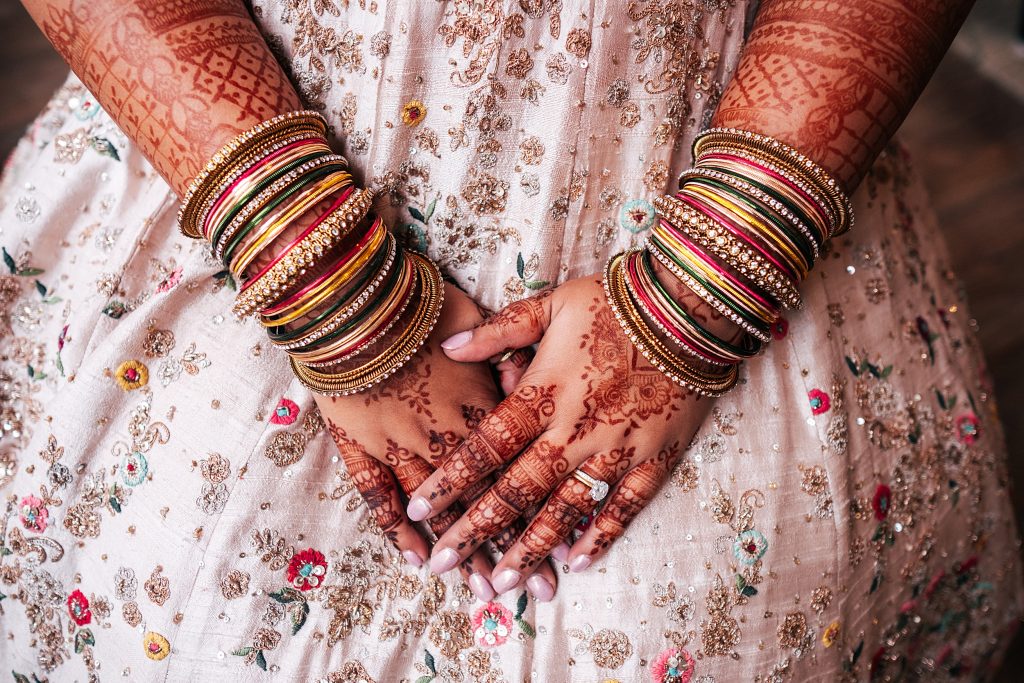 close up of brides bangles and her henna painted arms and hands