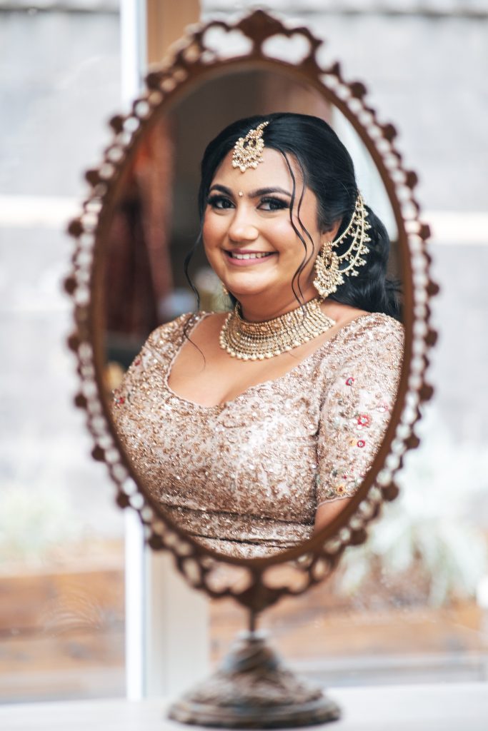 reflection in ornate mirror of smiling bride