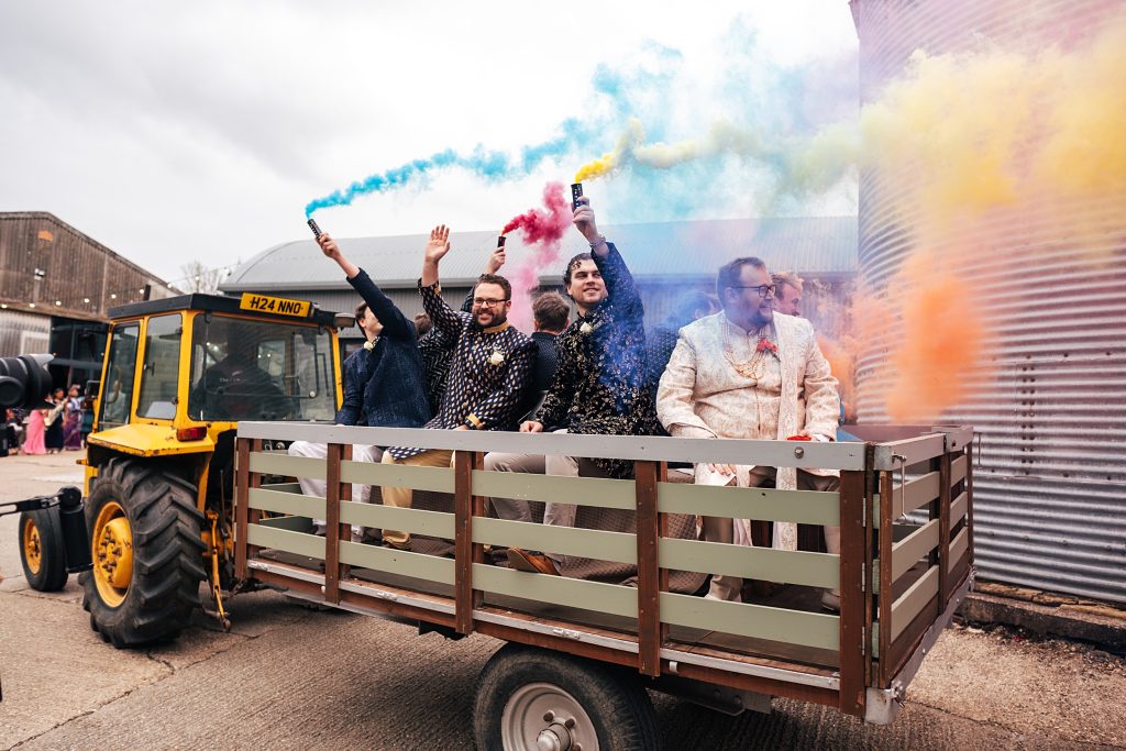 Groom with friends arrive for Jaan on tractor as they let off coloured smoke bombs