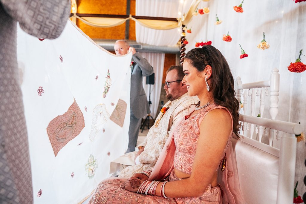 groom and his sister smile as they wait behind screen for Kanya Aagman