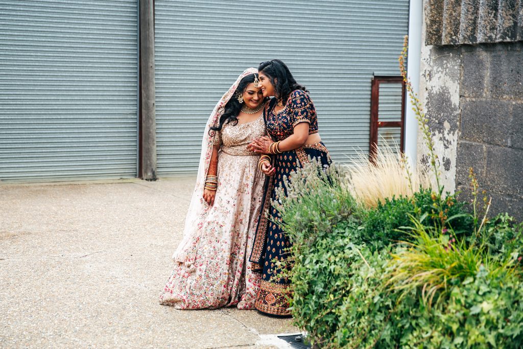 bride giggles with her sister as they wait for bride's entrance