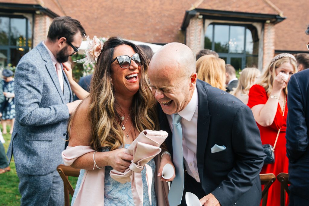 Guests bend over laughing during reception at Tuffon Hall Essex documentary wedding photographer