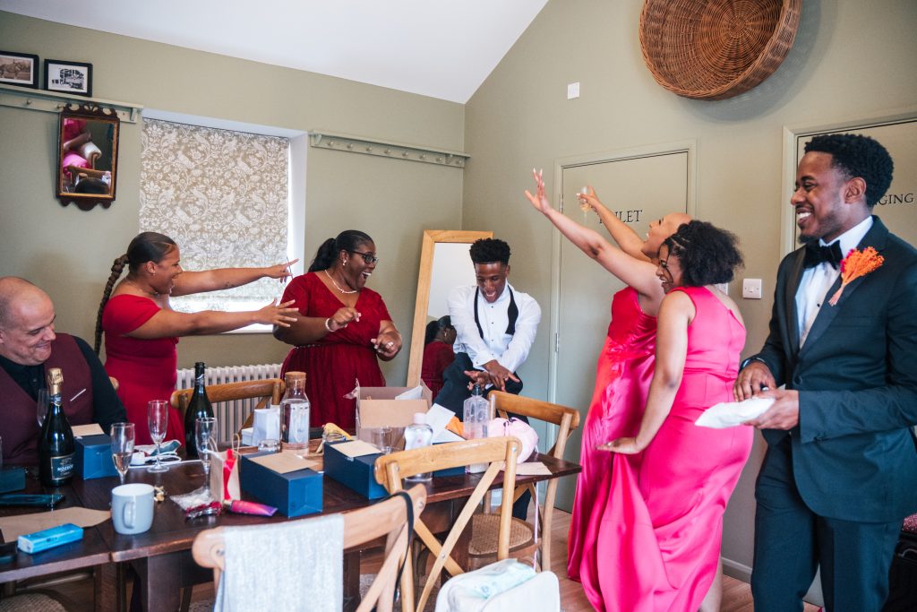 Groom and family dance during prep at The Barns at Lodge Farm Essex documentary wedding photographer
