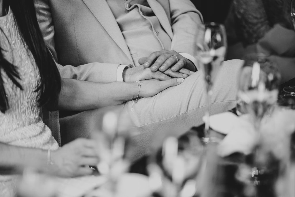 bride and groom hold hand during speeches Downham Hall Essex documentary wedding photographer