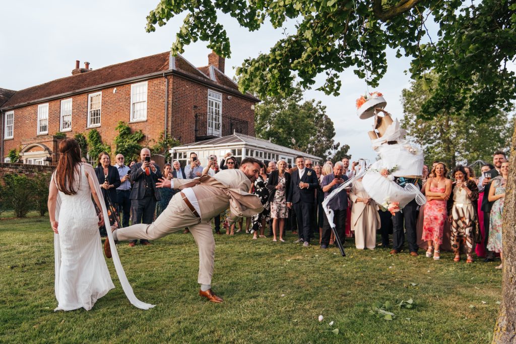 Groom hits pinata in tree at Downham Hall Essex documentary wedding photographer