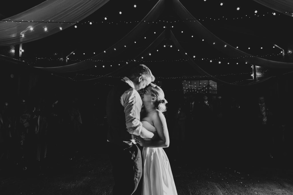 Bride and groom first dance under festoon lights and drapes at The Barns at Lodge Farm Essex documentary wedding photographer
