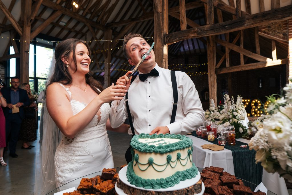 Groom licks knife after cutting cake at Tuffon Hall Essex documentary wedding photographer
